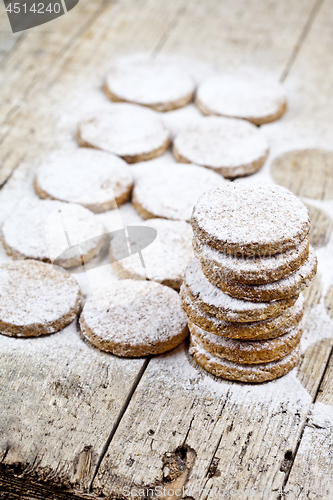 Image of Fresh baked oat cookies with sugar powder on rustic wooden table