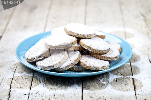 Image of Fresh baked oat cookies with sugar powderon blue ceramic plate o