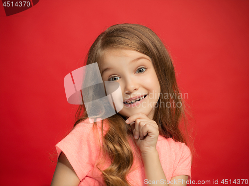 Image of The happy teen girl standing and smiling against red background.