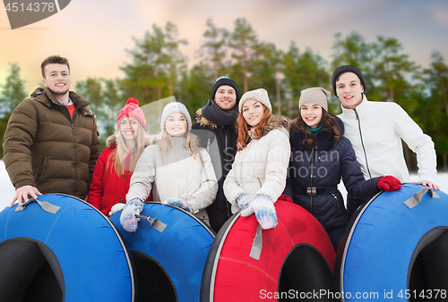 Image of happy friends with snow tubes outdoors in winter