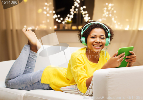 Image of woman with tablet pc and earphones on christmas