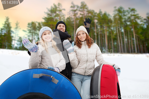 Image of happy friends with snow tubes outdoors in winter