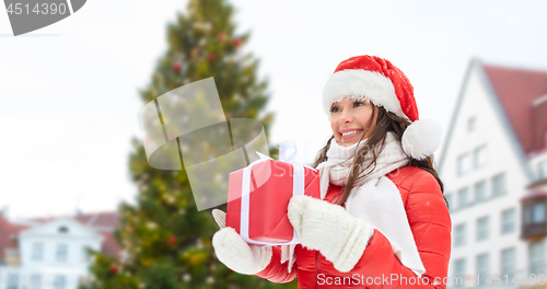 Image of happy woman with gift over christmas tree