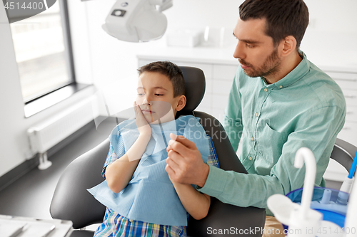 Image of father supporting son at dental clinic