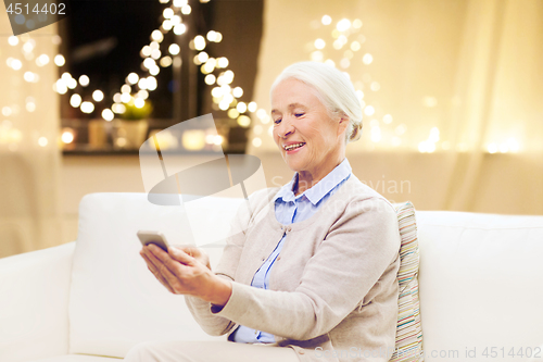 Image of senior woman with smartphone at home on christmas