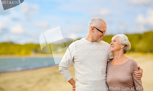 Image of happy senior couple hugging over beach background