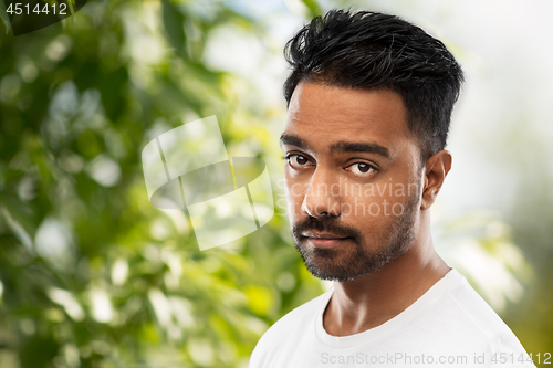 Image of sad young indian man over green natural background