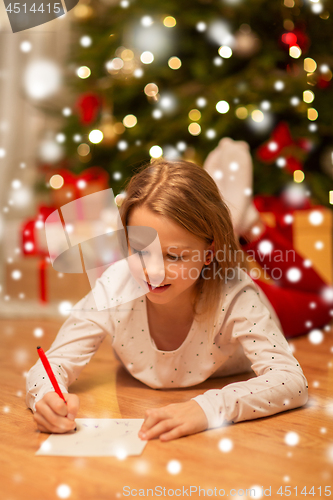 Image of smiling girl writing christmas wish list at home