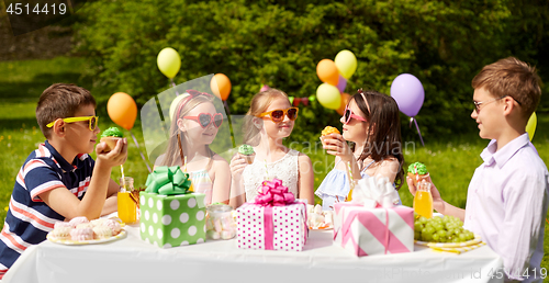 Image of kids eating cupcakes on birthday party in summer