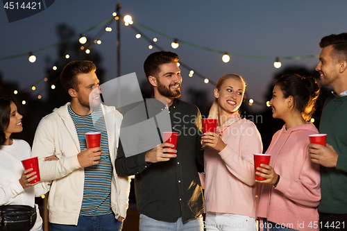 Image of friends with party cups on rooftop at night