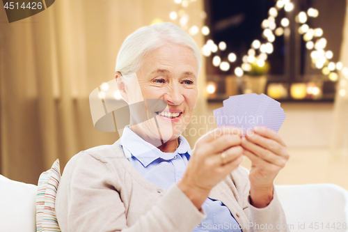 Image of happy senior woman playing cards on christmas