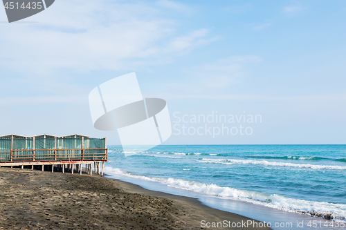 Image of Beautiful sea, the black sandy beach and white and blue striped beach houses