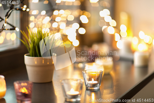 Image of candles burning on window sill with garland lights