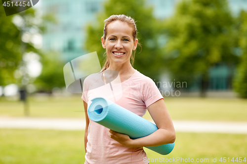 Image of happy smiling woman with exercise mat at city park