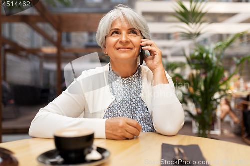 Image of senior woman calling on smartphone at street cafe