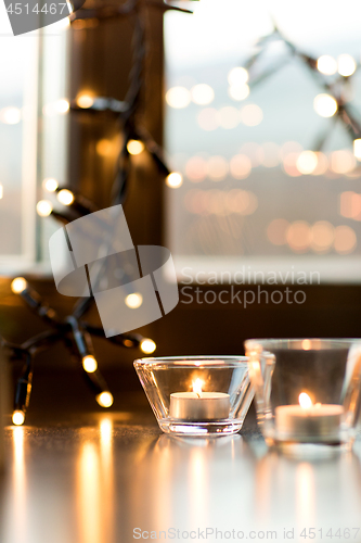 Image of candles burning on window sill with garland lights