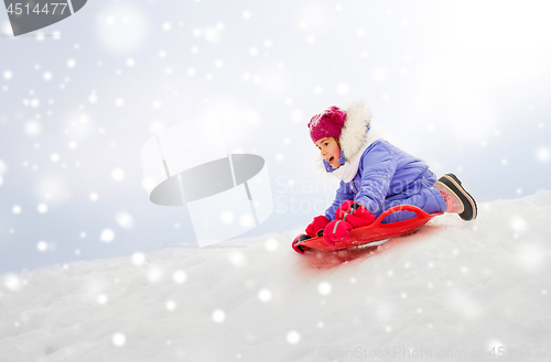 Image of girl sliding down on snow saucer sled in winter