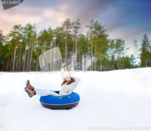 Image of happy teenage girl sliding down hill on snow tube