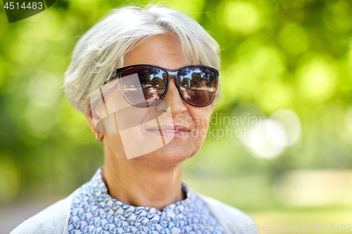 Image of portrait of happy senior woman at summer park