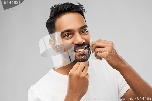 Image of indian man with dental floss cleaning teeth