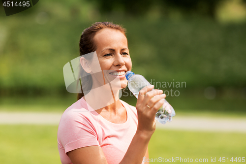 Image of woman drinking water after exercising in park