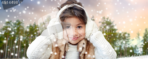 Image of little girl wearing earmuffs over winter forest