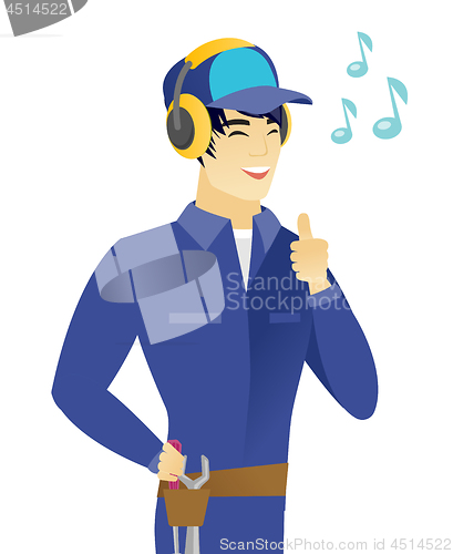 Image of Asian mechanic listening to music in headphones.