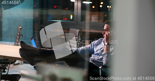Image of businessman sitting with legs on desk at office