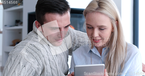 Image of Young Couple using digital tablet on the floor