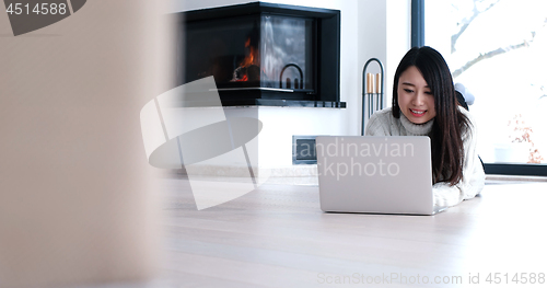 Image of Asian woman using laptop on floor