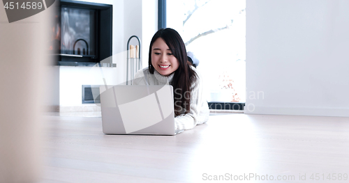 Image of Asian woman using laptop on floor