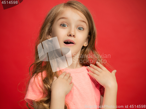 Image of The happy teen girl standing and smiling against red background.