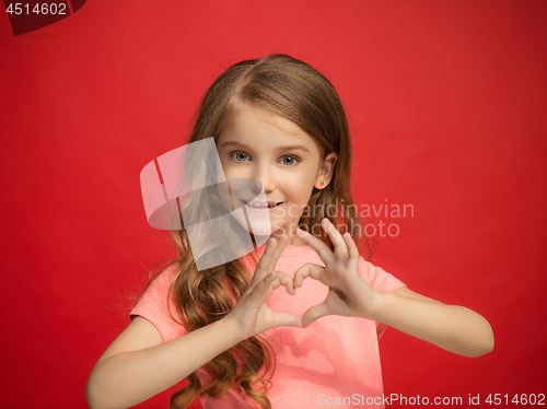 Image of The happy teen girl standing and smiling against red background.