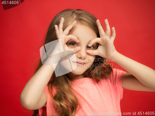 Image of The happy teen girl standing and smiling against red background.