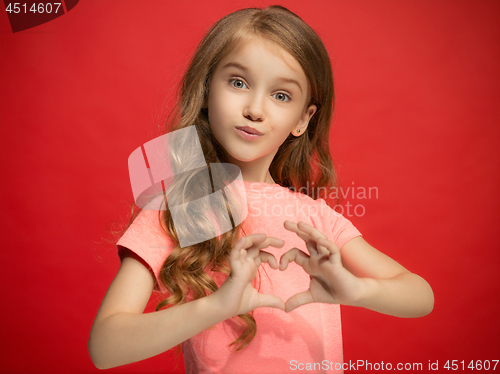 Image of The happy teen girl standing and smiling against red background.