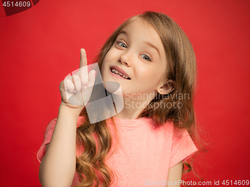 Image of The happy teen girl standing and smiling against red background.