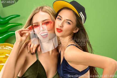 Image of Cute girls in swimsuits posing at studio. Summer portrait caucasian teenagers on green background.