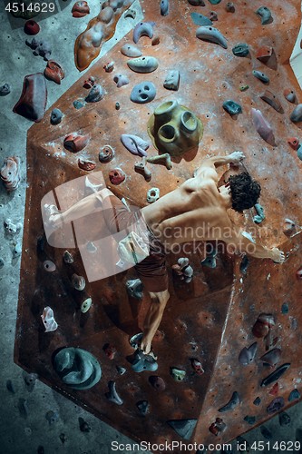 Image of Free climber young man climbing artificial boulder indoors