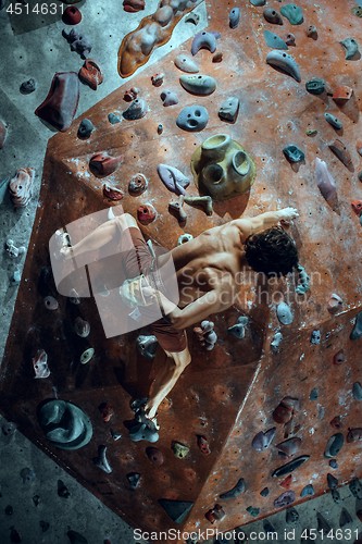 Image of Free climber young man climbing artificial boulder indoors