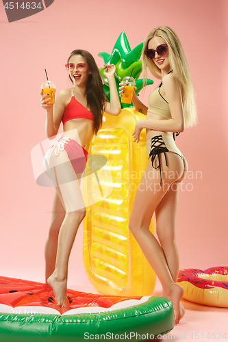 Image of Cute girls in swimsuits posing at studio. Summer portrait caucasian teenagers on pink background.