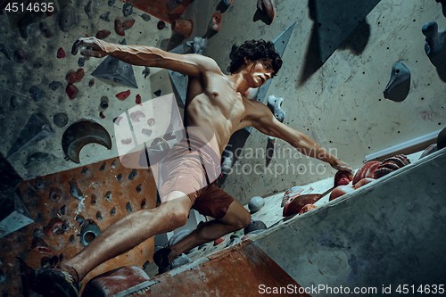 Image of Free climber young man climbing artificial boulder indoors