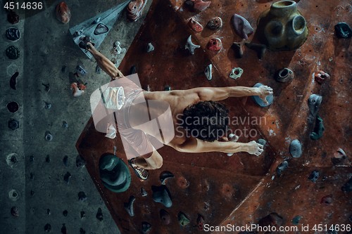 Image of Free climber young man climbing artificial boulder indoors