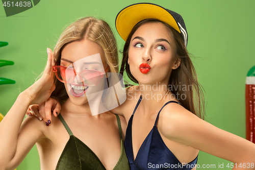 Image of Cute girls in swimsuits posing at studio. Summer portrait caucasian teenagers on green background.