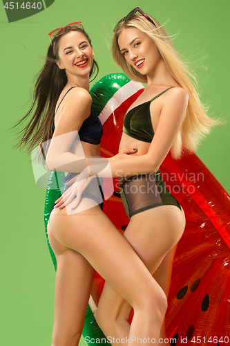 Image of Cute girls in swimsuits posing at studio. Summer portrait caucasian teenagers on green background.