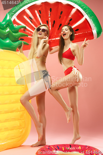 Image of Cute girls in swimsuits posing at studio. Summer portrait caucasian teenagers on pink background.