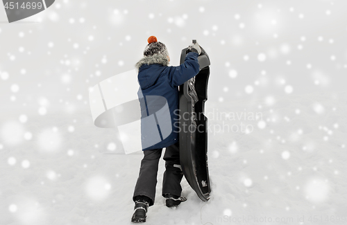 Image of little boy with sled climbing snow hill in winter