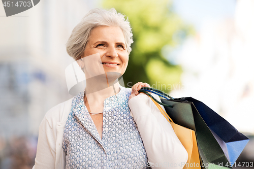 Image of senior woman with shopping bags in city