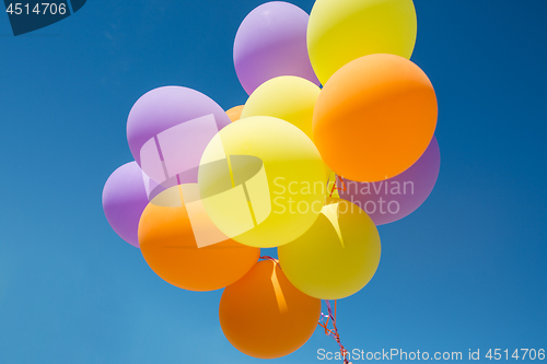 Image of close up of colorful helium balloons in blue sky