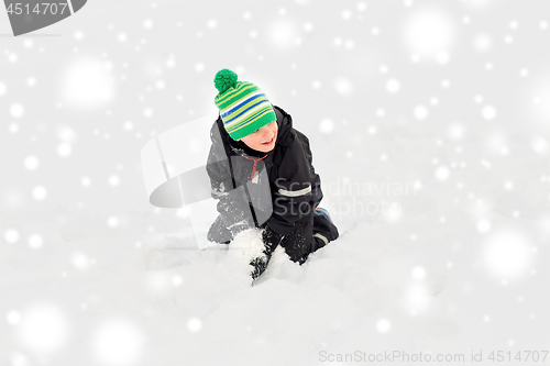 Image of happy little boy playing with snow in winter