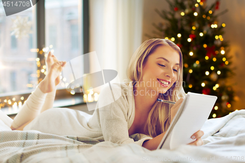 Image of woman making wish list at home on christmas